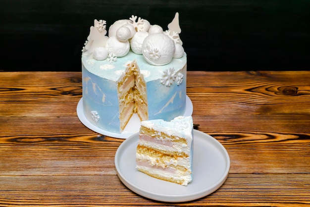 Pan di spagna bianco blu cocco deliziosa vaniglia glassa cremosa torta decorata con grandi fiocchi di neve rotondi al cioccolato marshmallow abeti immagine di montagna pezzo tagliato dolce dessert con strato di fragole