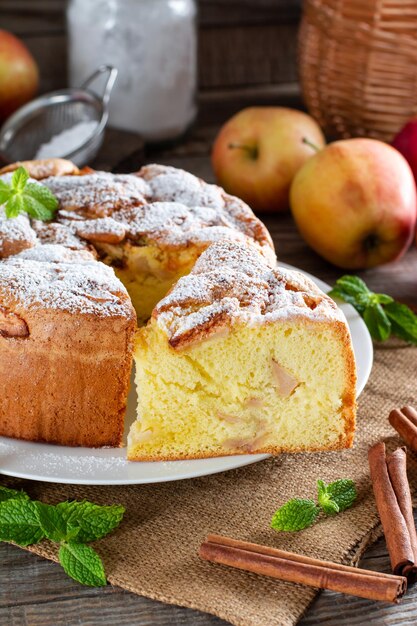 Pan di Spagna classico con le mele sul tavolo di legno. Torta fatta in casa