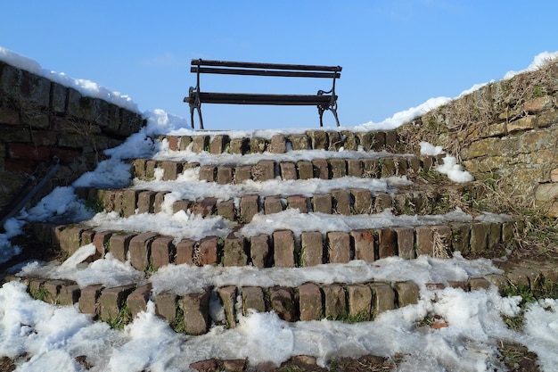 Panca solitaria e scale coperte di neve