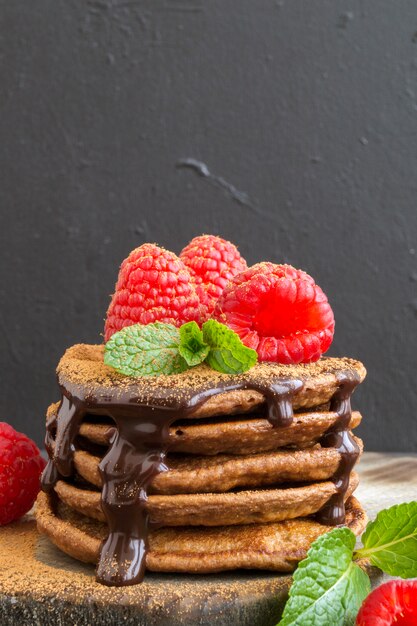 Pancake al cioccolato con lampone su uno sfondo scuro.