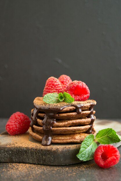 Pancake al cioccolato con lampone su uno sfondo scuro.