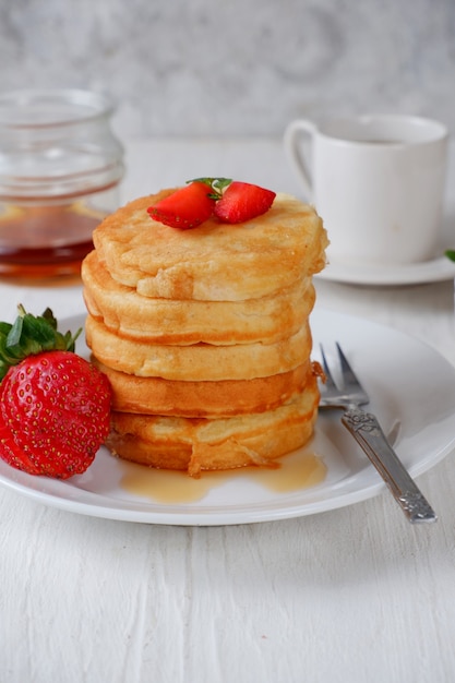 Pancake con fragole e miele su bianco