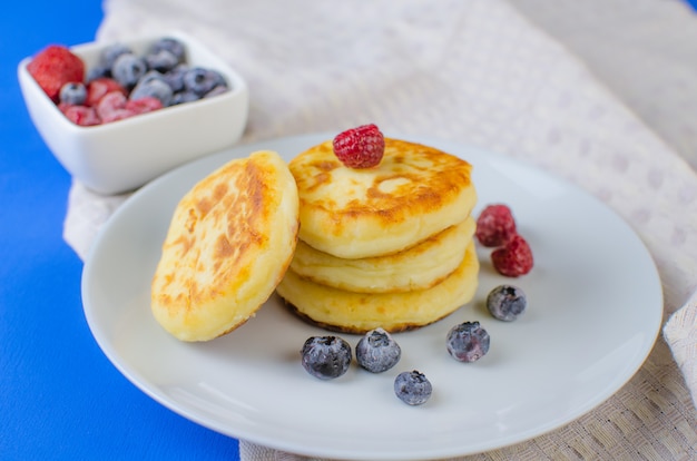 Pancake con fragole, lamponi, mirtilli su una superficie blu