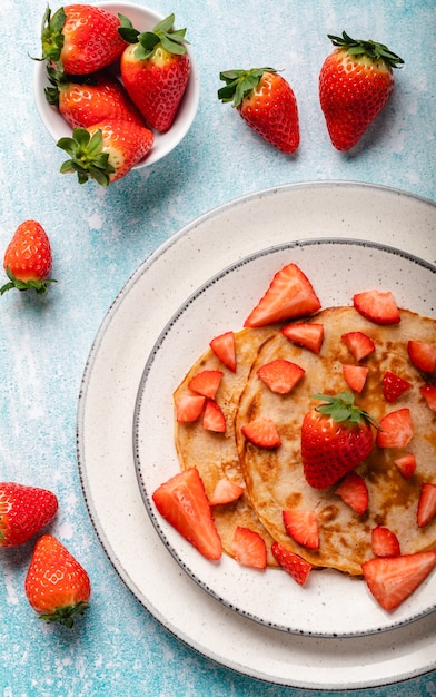 Pancake con la fragola fresca su una parete di legno blu