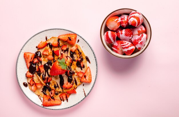 Pancake con la fragola fresca su una parete di legno blu