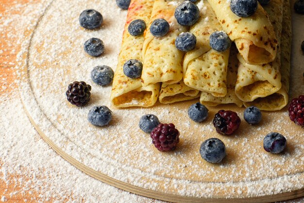 Pancake con marmellata di bacche, bacche e zucchero in polvere closeup