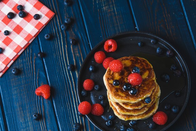 Pancake con miele e le bacche su una tavola di legno