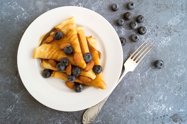 Pancake con sciroppo di noci e mirtilli. su un piatto bianco