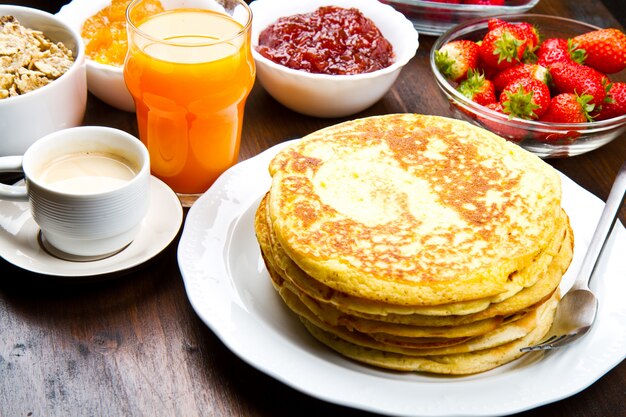 Pancake deliziosi sulla tavola di legno con i frutti