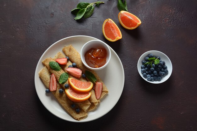 Pancake dolci avvolti con menta fresca fragole mirtilli arance e marmellata