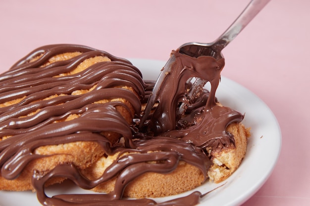 Pancake fresco in un piatto versato con pasta di cioccolato, crema sui panini, pancake al cioccolato