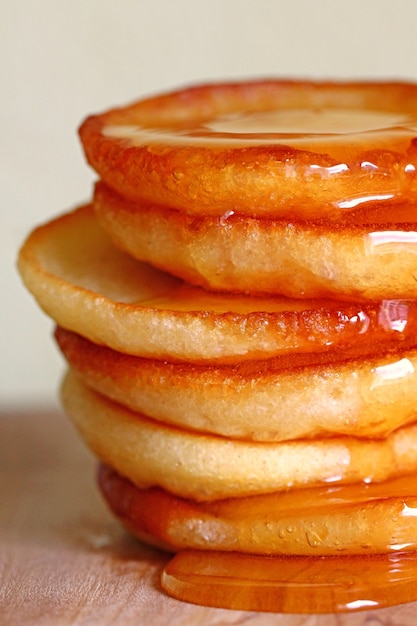 Pancake in un mucchio di miele su una luce offuscata parete