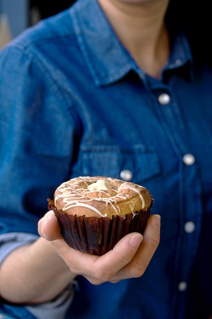 Pancake o Cinnamon Roll tenuto in mano di una donna nel cibo da dessert della caffetteria