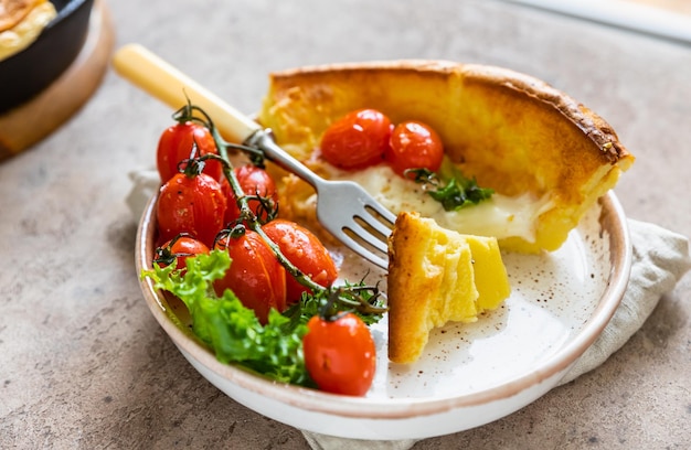 Pancake olandese salato con pomodori arrosto, mozzarella e foglie di insalata Cucina danese