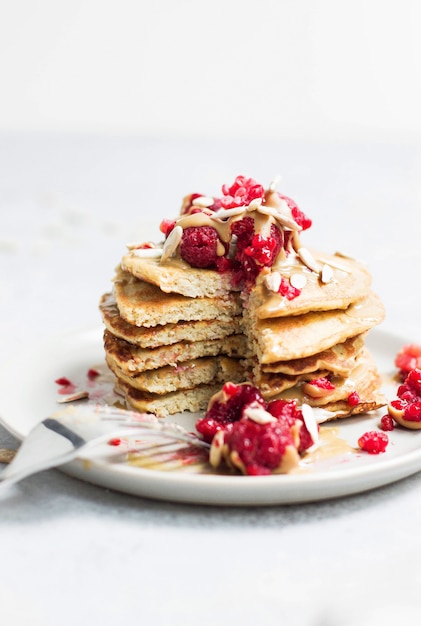 Pancake saporiti con il primo piano dei girasoli e dei lamponi su bianco