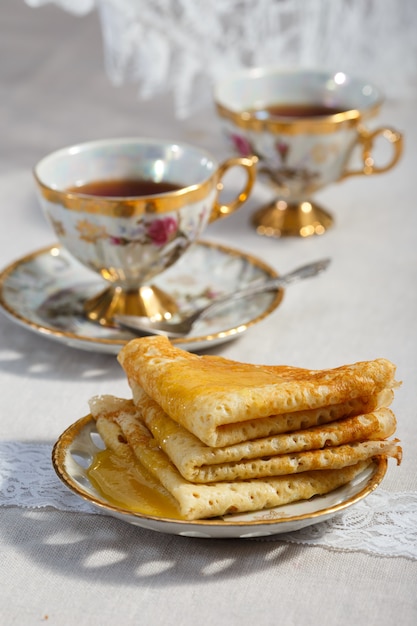 Pancake sottili su un piatto e una tazza di tè