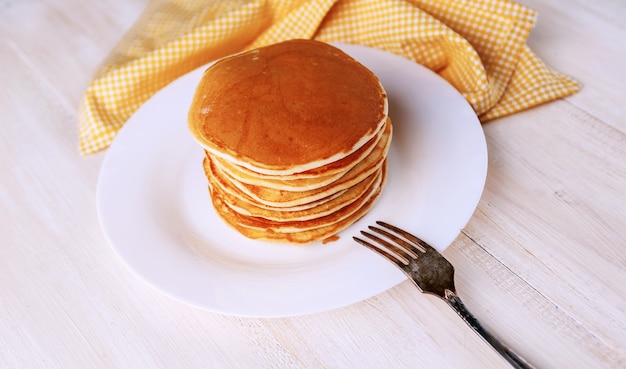 Pancake su un piatto bianco su un fondo di legno