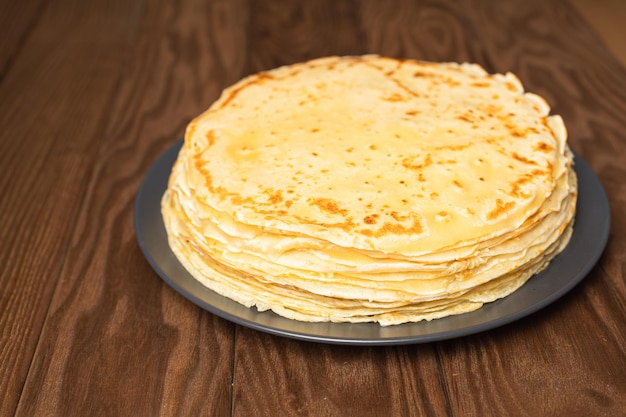 Pancake sul piatto isolato su priorità bassa bianca. Mucchio di frittelle sottili in stile russo per le vacanze Maslenitsa. Sfondo di cibo per colazione e carnevale.