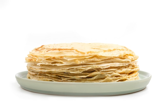 Pancake sul piatto isolato su priorità bassa bianca. Mucchio di frittelle sottili in stile russo per le vacanze Maslenitsa. Sfondo di cibo per colazione e carnevale.