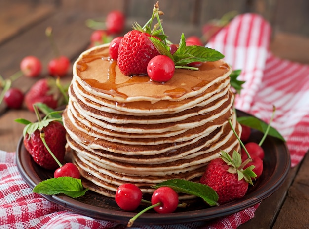 Pancakes con frutti di bosco e sciroppo in stile rustico