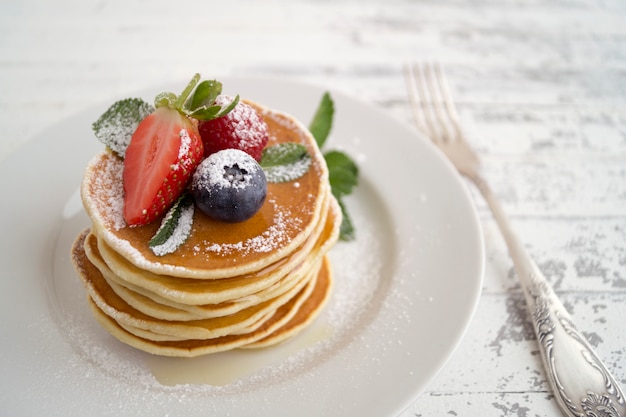 Pancakes con lamponi, fragole e mirtilli per colazione.