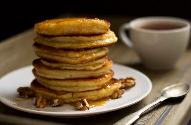 Pancakes con miele e noci, una tazza di tè, colazione