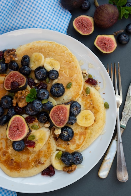 Pancakes con mirtilli, frutta secca e miele. Colazione con caffè e pancake.