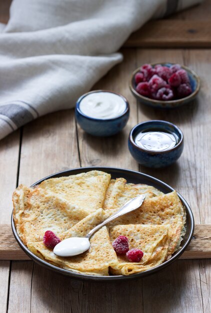 Pancakes serviti con panna acida, lamponi e miele. Il piatto tradizionale di Carnevale e Maslenitsa.