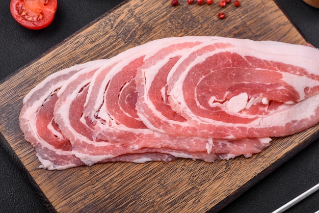 Pancetta cruda fresca affettata con spezie ed erbe aromatiche