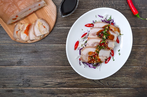 Pancetta di maiale con insalata di cavolo in una ciotola bianca su uno sfondo di legno. Cucina cinese. Vista dall'alto.