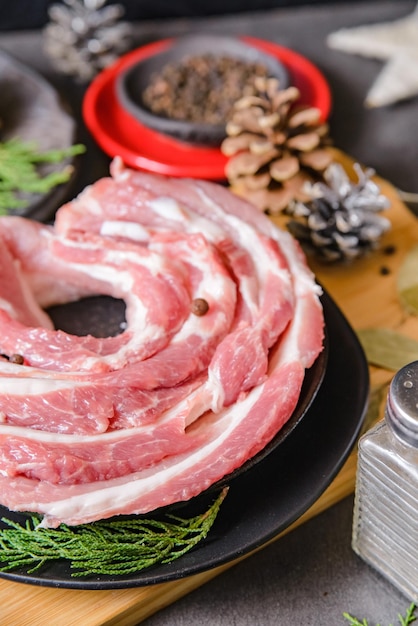 Pancetta di maiale cruda affettata per preparare una cena per un piatto di Natale con decorazioni natalizie