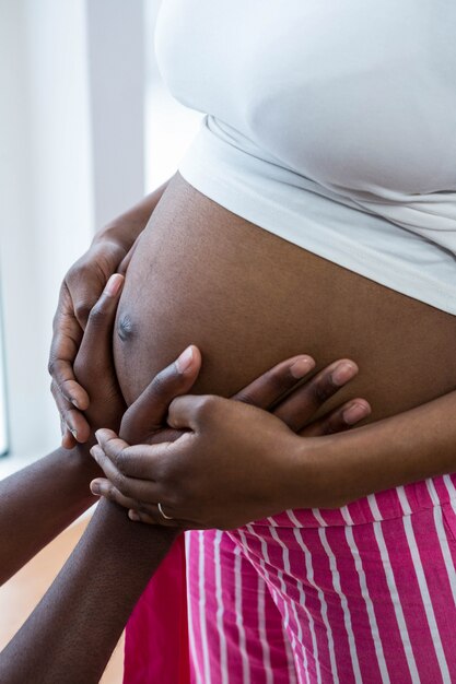 Pancia commovente della donna incinta dell'uomo a casa