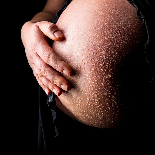 Pancia della donna incinta con gocce d'acqua