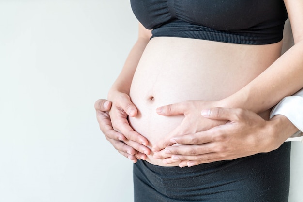 Pancia della donna incinta con le mani e le mani del marito