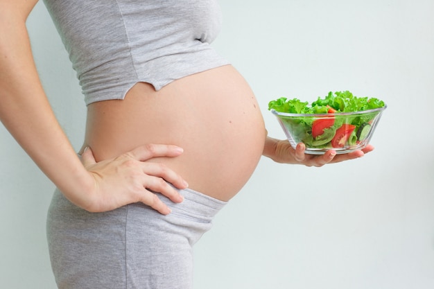 pancia della donna incinta e insalata di verdure