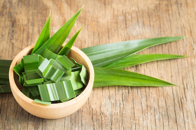 Pandan verde fresco in una ciotola di legno sulla tavola di legno, foglie pandan su vecchio fondo di legno