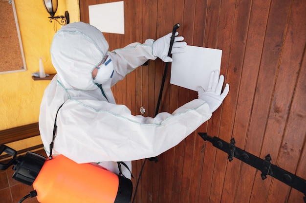 Pandemia di coronavirus Un disinfettante in una tuta protettiva e spray per maschere