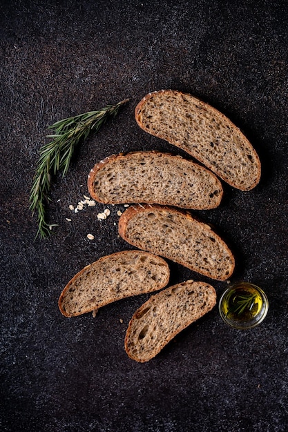 Pane a base di lievito tagliato con farina integrale e semi di zucca su una griglia di olio d'oliva e oliva nera