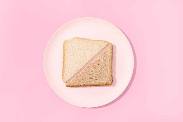 Pane a fette di pane bianco e integrale su piatto su sfondo rosa Disposizione piatta