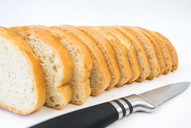 Pane a fette e un coltello su sfondo bianco Fette di pane bianco Baton su sfondo bianco