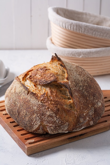 Pane a lievitazione naturale su una tavola di legno con accessori per la cottura