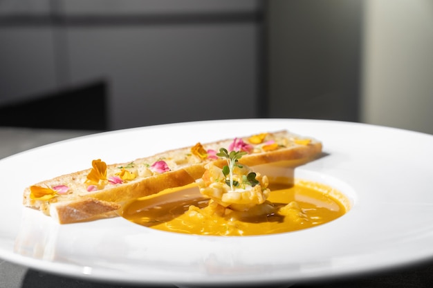 Pane all'aglio con zuppa cremosa TomYamKung su piatto bianco in luce da studio decorato con petali di fiori su di esso