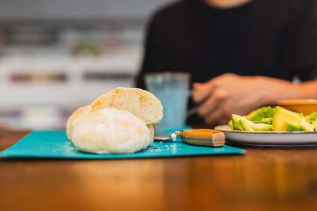 Pane appena affettato sul tagliere con uomo che tiene in mano una tazza di caffè