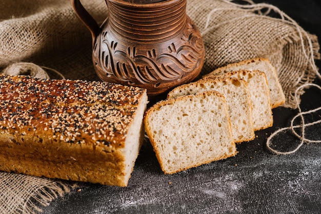 Pane appena sfornato con vaso e tessuto sullo sfondo di legno nero