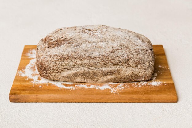 Pane appena sfornato sul tagliere contro il pane bianco di vista prospettica del fondo di legno con lo spazio della copia