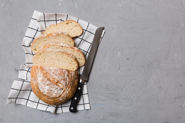 Pane appena sfornato tagliato con un coltello su una tavola di legno vista dall'alto Pane a fette e coltello