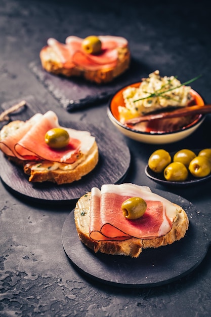 Pane arrosto con crema di burro all'aglio e prosciutto di serano e olive