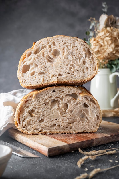 Pane artigianale fatto in casa a lievitazione naturale tagliato a metà su sfondo scuro.