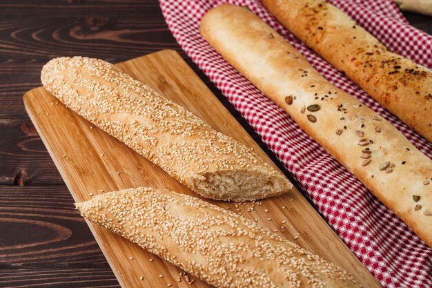 Pane baguette sul bordo di legno marrone vicino foto