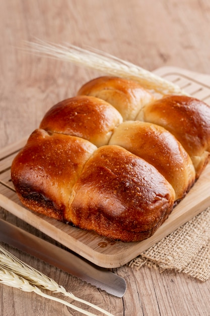 Pane brasiliano fatto in casa su un piano di lavoro in legno, con farina spalmata sul bancone e grano.